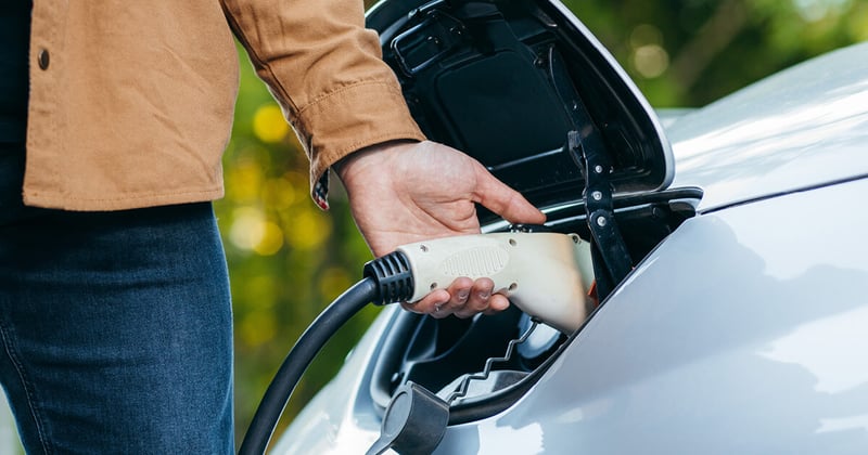 Lähikuva sähköautosta ja sen latauspistokkeesta.