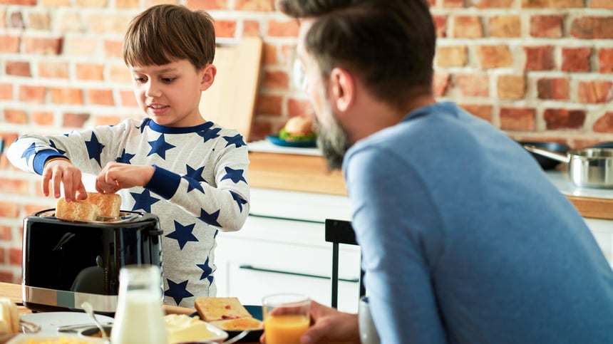 pieni-poika-paahtaa-leipää-isän-vahtiessa