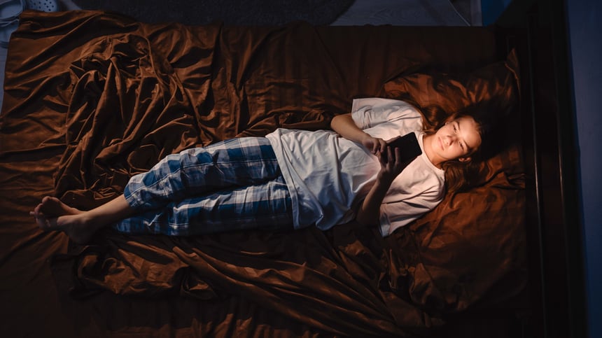 tyttö-tutkii-älypuhelinta-yöllä-sängyssä