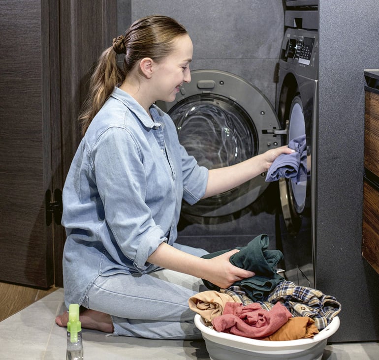 nuori-nainen-ottaa-pyykkia-koneesta-ulos