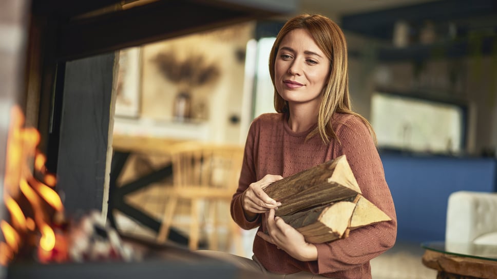 nainen_lisaa_puita_takkaan