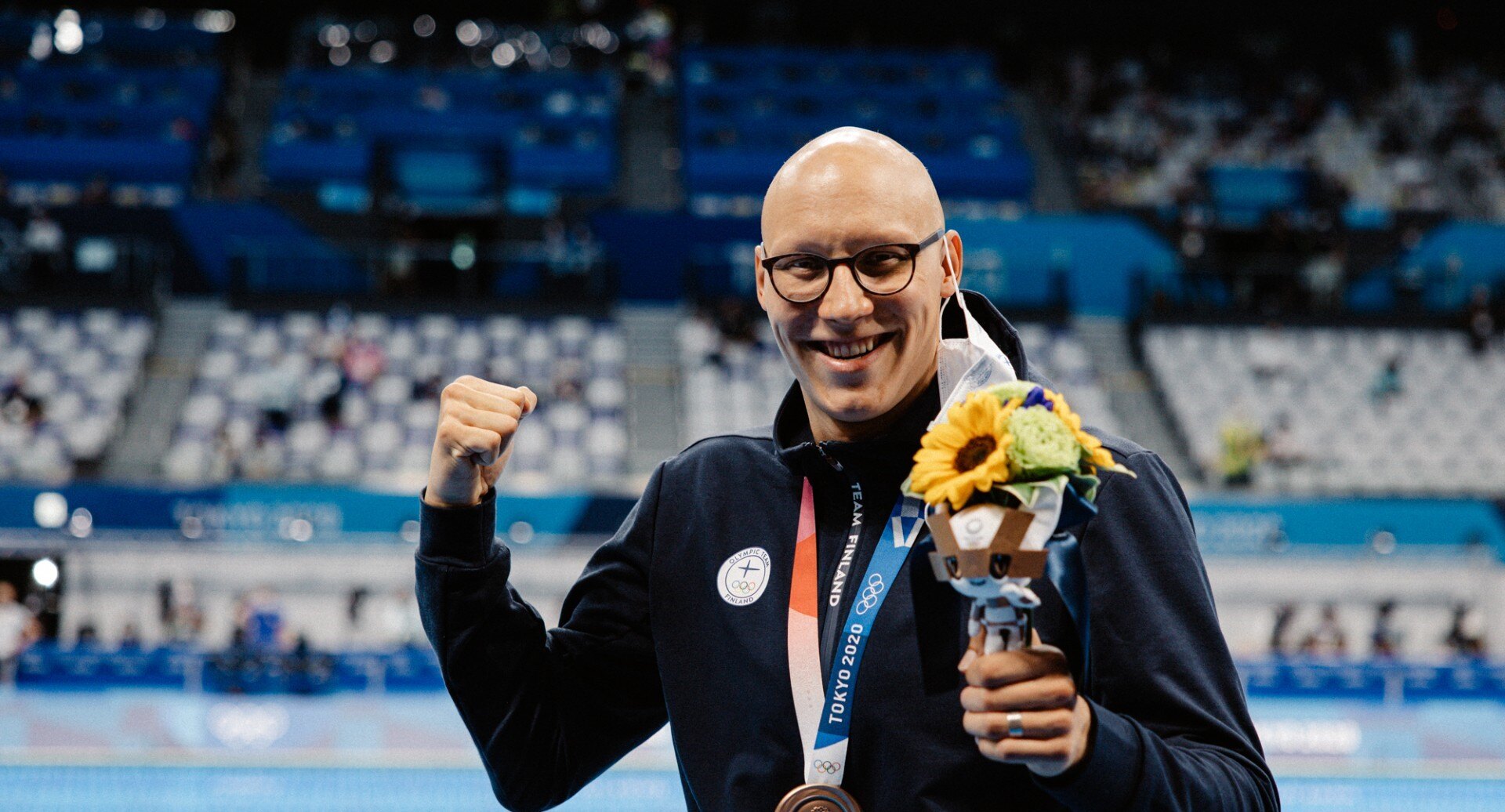 Matti Mattsson tuulettaa Tokion olympialaisissa pronssimitali kaulassaan ja kukkakimppu kädessään.