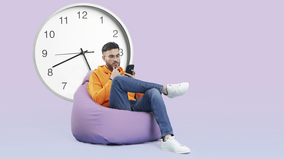 mies istuu säkkituolissa ja tutkii kännykkäänsä