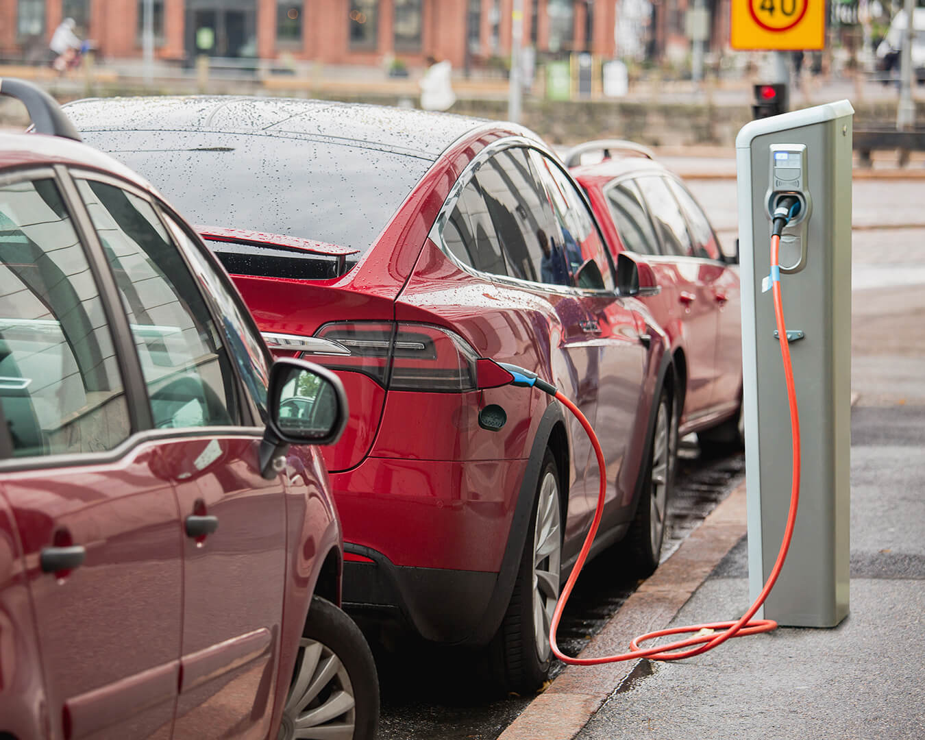 Sähköauto on pysäköitynä kadunvarren lataustolpalle.